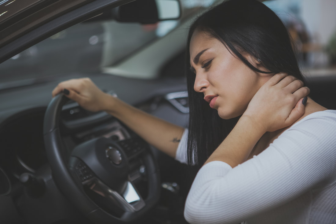 Driver holding her neck in pain inside a car after an accident
